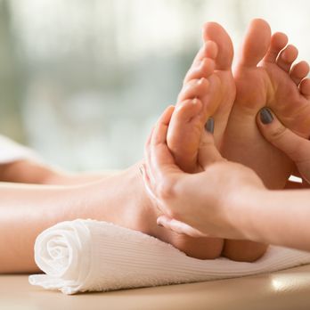 Fußmassage mit einer Hand, die den Fuß an einen Handtuch rollt. Entspannende Atmosphäre.